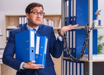 Young man standing next to the shelf with folders