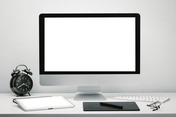 Stylish workspace with blank screen computer display and tablet for mockup on work desk with keyboard, mouse, clock, eyeglasses and pen tablet.