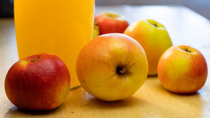 Background with a big bottle of apple juice and fresh apples that lie on the table.