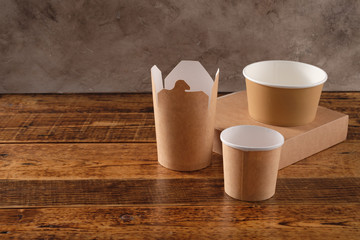 Street fast food paper cups, plates and containers. Eco-friendly food packaging on wooden background. Carering of nature and recycling concept.