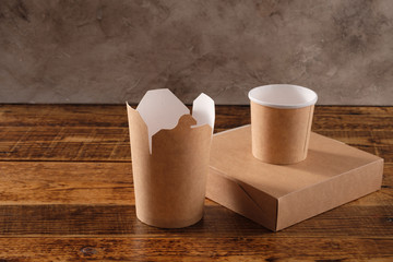 Street fast food paper cups, plates and containers. Eco-friendly food packaging on wooden background. Carering of nature and recycling concept.