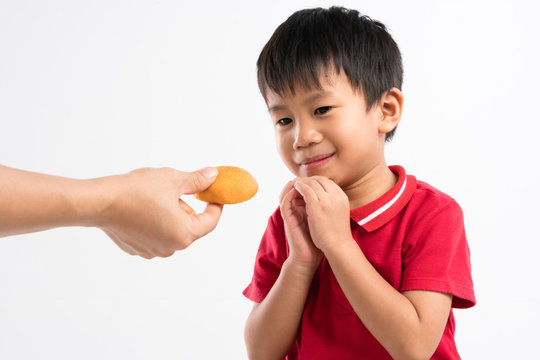 Hand giving sweet cake snack to 4 years old Asian boy