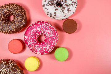 Tasty donuts and macaroons on pink background. Top view