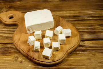 Feta cheese on cutting board on a wooden table