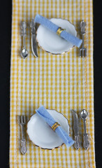 table setting - two plates and silverware on checkered tablecloth flat lay