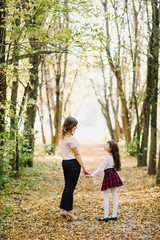 happy mom and daughter fall in Park holding hands and smiling