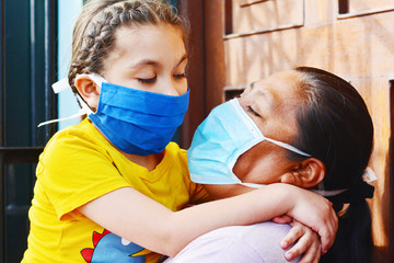 Tender portrait of native american mom with her little daughter. Both wearing masks.