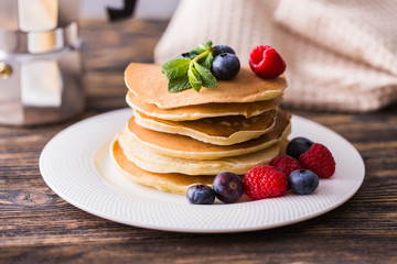 Pancakes with blueberries and raspberry on wooden background. Breakfast and traditional meal.