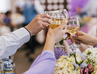 hands of a group of friends clinking glasses of wine and toasting