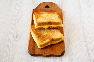 Homemade Grilled Cheese Sandwich on a rustic wooden board on a white wooden background, low angle view. Space for text.