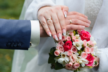 hands of the bride and groom with wedding gold rings on the background of a beautiful bouquet