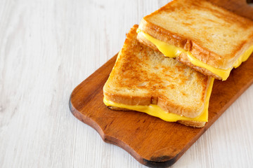 Homemade Grilled Cheese Sandwich on a rustic wooden board on a white wooden surface, low angle view. Copy space.