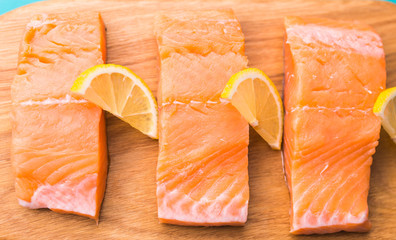 Delicious salmon steak on wooden cutting board, close-up.