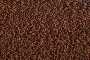 Brown background of sprinkled instant coffee with a strong increase