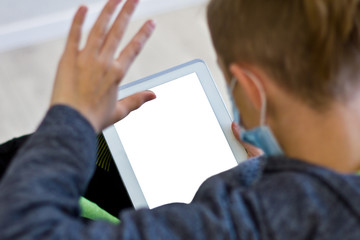 Young man in casual conversation over video call on tablet in protective mask due to spread of coronavirus epidemic