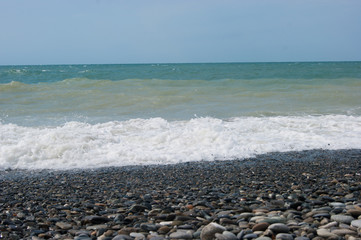 The sea is worried once - a little muddy water of the Black Sea after a small storm. The sea, clear sky and smooth horizon line, wave, wet large pebbles on the beach.