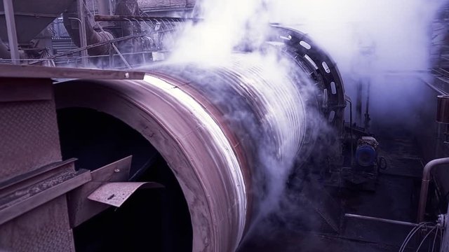 Old equipment of heavy metallurgical industry. Stock footage. Cooling unit with rotating tank under water jet at metallurgical enterprise