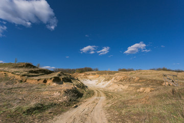 road through an empty field under the clouds