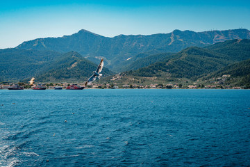 White yachts and catamarans in a bay near a tropical island. Sailing yacht and motor catamaran for charter and bareboat in the lagoon by the beach. Blue sea, white vessels during sport ocean cruise