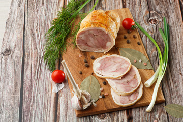 Chicken roll in grid decorated lettuce leaf isolated on wooden background. Fresh meat product whole and partly sliced. Chicken ham, and slices of tasty chicken meat. Natural product from organic farm.