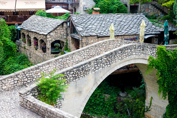 The ancient city of Mostar, Bosnia and Herzegovina. View of an alley with a river and a bridge in a...