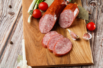 Industrial manufacture of sausages. Smoked sausage on a wooden rustic table with addition of fresh aromatic herbs and spices, natural product from organic farm, produced by traditional methods.