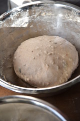 Handmade bread dough rising in a stainless steel bowl