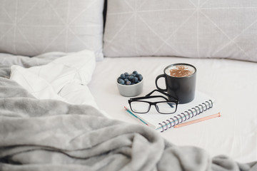 Morning coffee in bed. Working or Studying from home. Coffee, blueberries, glasses, pen and note book. Work from home