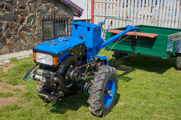 walking tractor with trailer,mini tractor on two wheels with a trailer in the yard, a motor block with a trailer