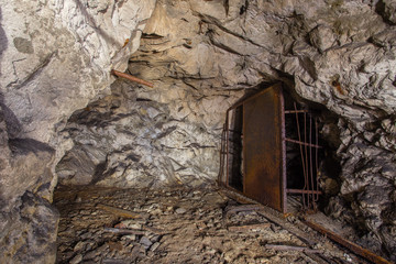 Underground old abandoned iron mine tunnel with rusty door