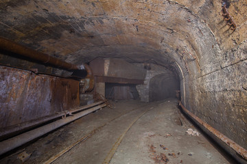 Fototapeta na wymiar Underground abandoned iron ore mine tunnel with concrete timbering and rails