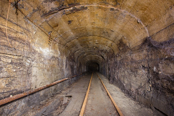 Fototapeta na wymiar Underground abandoned iron ore mine tunnel with concrete timbering and rails