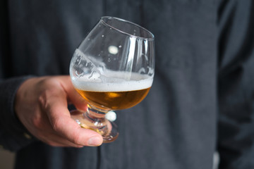 A glass of beer in the hands of a man. Tasting brewed craft beer. Lager beer with beautiful foam....