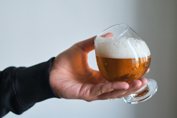 A glass of beer in the hands of a man. Tasting brewed craft beer. Lager beer with beautiful foam. Cold refreshment beverage. Alcohol drink from pub. Relaxation and enjoyment on beer degustation
