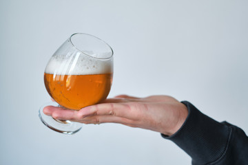A glass of beer in the hands of a man. Tasting brewed craft beer. Lager beer with beautiful foam. Cold refreshment beverage. Alcohol drink from pub. Relaxation and enjoyment on beer degustation