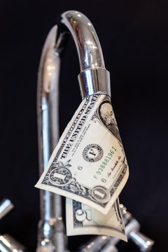 Abstract picture showing how we waste money through leaking taps with dollar bill coming out of the faucet