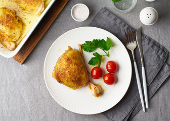 Chicken thighs baked with turmeric, tomatoes and garlic. Fried chicken is on plate
