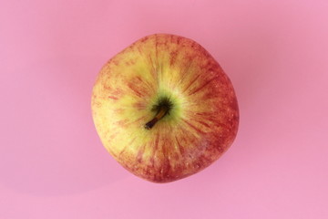 Red yellow apple on a pink background. Juicy ripe beautiful fruit.