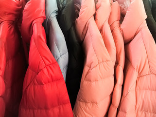 Multi colors of down jackets on the hangers at the store for sell. Collection of winter coats...