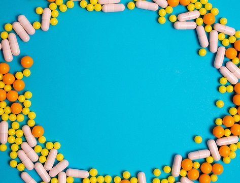 Colorful Pills For Viral Diseases In Circle Frame With Copyspace For Text. Prevention Of Influenza, Coronavirus, Covid-19. Yellow, Orange, White Vitamins On Blue Background. Medical Healthcare Concept