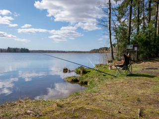 Fototapeta na wymiar landscape with a lake and beautiful cloud reflections, fishing accessories on the lake shore