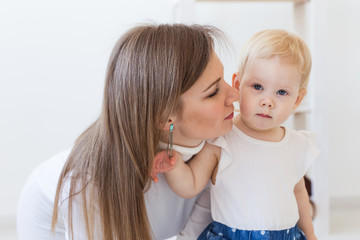 Young mother playing with her baby girl at home. Motherhood, infant and children concept.