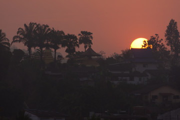 Fototapeta na wymiar Beautiful Sunrise Behind a Temple and Palms at Laos, seen from Chiang Khong, Thailand, Asia