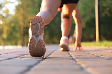 Runner feet running on road closeup on shoe, outdoor at sunset or sunrise.