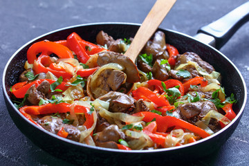 Chicken liver on a skillet with a wooden spoon