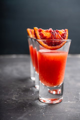 Strong red cocktail in shots on the rustic background. Selective focus. Shallow depth of field.