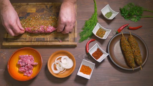 Lulia kebab, a dish of Georgian cuisine. Process of making kebab lula, top view. Chef cooks a lula kebab from raw minced meat and sprinkled with spices. Spices and ingredients stand on the table.