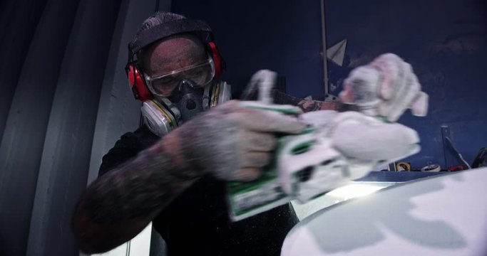 Close up of man shaping surfboard with electrical sander