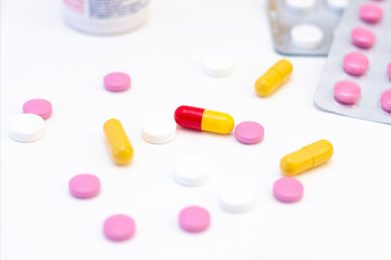 pills and capsules of different colors on the background of many drugs. The concept of health care, treatment, illness.
