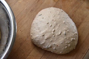 Dough for sourdough bread with nuts and seeds on a wooden table